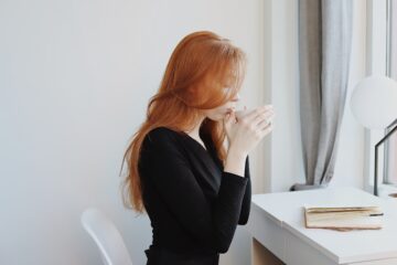 woman sitting at desk sipping from a mug
