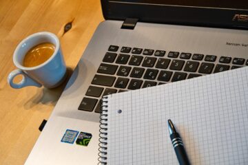 coffee cup next to open laptop and notebook, ready for online training
