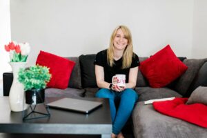 the chronic entrepeneur lisa porto on her sofa in her home, holding a cup of tea and smiling