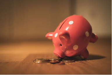 piggy bank facing some small coins, representing rising costs of business