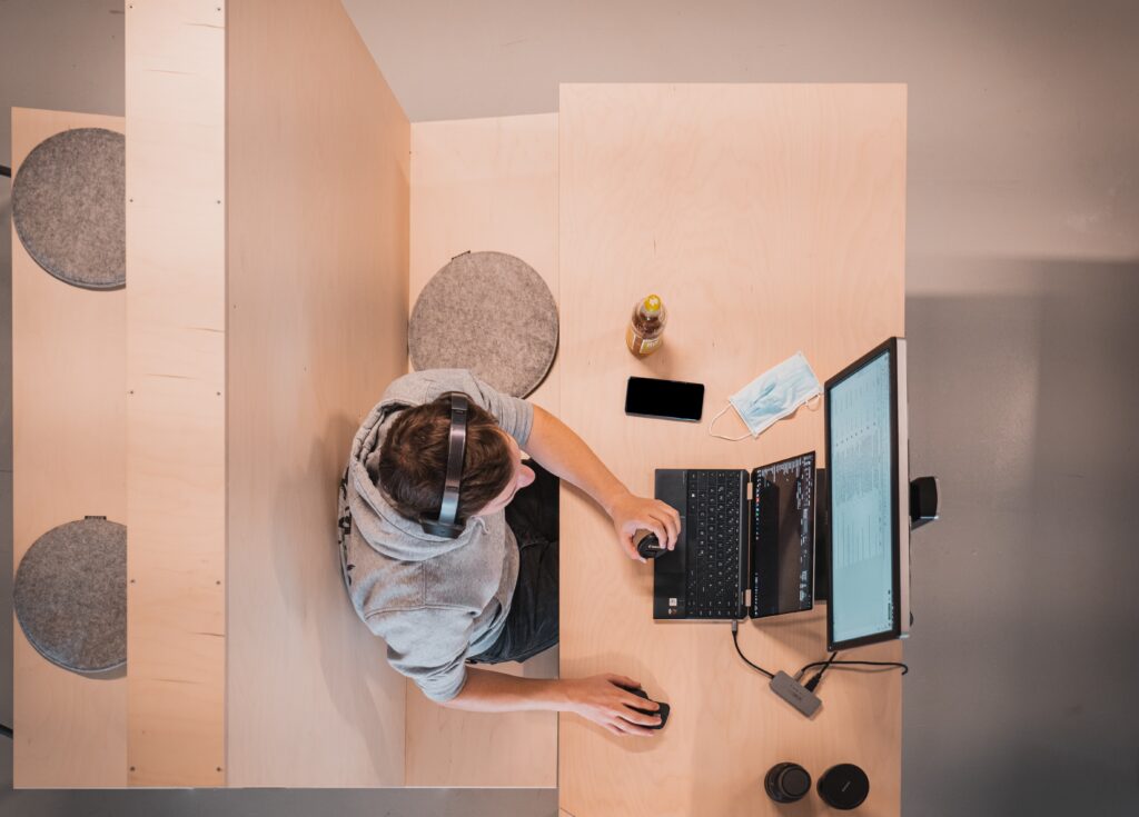 birdys eye view of somebody sat at a wooden desk working at a computer, representing finding a new career with chronic illness