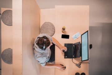 birdys eye view of somebody sat at a wooden desk working at a computer, representing finding a new career with chronic illness